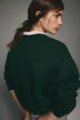 Buzo verde oscuro con cuello redondo, hombros caídos y un diseño frontal dorado que incluye una corona, un escudo y las palabras "Milano Firenze" y "La moda dal cuore". Tiene remates acanalados en cuello, puños y bajo, y un interior cepillado suave.