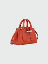 Cartera de mano modelo Le Roseau XS de Longchamp, confeccionada en cuero color verde oliva. Presenta un diseño estructurado con el icónico cierre de bambú metálico en la parte frontal y doble asa corta.