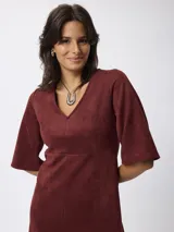 Vestido corto de gamuza sintética color bordó, con escote en V, mangas tres cuartos acampanadas y corte entallado en la cintura.