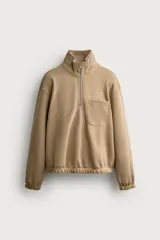 Sudadera regular fit de color beige, confeccionada en tejido con algodón, con cuello subido, cierre frontal de cremallera parcial, manga larga, bolsillo plastrón en el pecho y acabados en rib elástico.