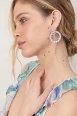 Caravanas de diseño colgante formadas por dos aros entrelazados, completamente engastados con pedrería brillante plateada.