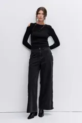 Blusa de punto acanalado color negro, con diseño de hombros descubiertos y manga larga.