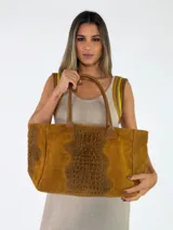 Cartera tipo tote de cuero color beige con textura gamuzada y detalles con grabado de cocodrilo en el centro y los laterales. Cuenta con doble asa de hombro.