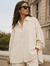 Camisa oversize de lino, color beige, con cuello camisero clásico, cierre frontal con botones, mangas largas con puños abotonados y bolsillo frontal aplicado.