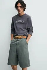 Bermuda tipo jorts de algodón color verde oscuro, con corte relajado y tiro medio. Presenta bolsillos frontales y bolsillos traseros de plastrón.