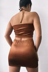 Minivestido marrón de satén con escote halter, abertura en el pecho y recortes laterales.