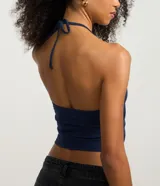 Top cropped de algodón color amarillo pálido, con escote en V pronunciado y tirantes finos que se atan en la nuca (estilo halter). El tejido es acanalado.