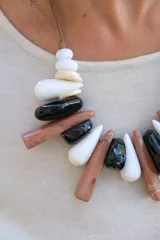 Collar de diseño artesanal compuesto por piezas de resina en forma de gotas y cilindros alargados en tonos blanco, negro y marrón, montadas sobre un cordón de hilo encerado.