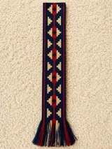 Faja tejida en telar de mano con diseño geométrico multicolor en tonos azul marino, beige y rojo, con flecos en los extremos.