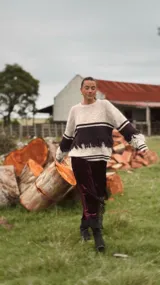 Sweater de punto con diseño de bloques de color en tonos beige y bordó, con cuello redondo, mangas largas y detalle de flecos decorativos en el cuerpo y las mangas.