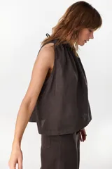 Blusa de lino italiano color marrón oscuro, con corte en línea A, hombros descubiertos, escote halter con frunces y volado en el cuello.