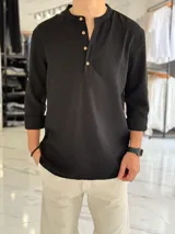 Camisola de lino negra, de manga larga con puños arremangados, cuello mao y cierre frontal parcial con botones de madera.