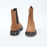 Botines estilo Chelsea de material sintético color marrón, con paneles elásticos laterales, cierre lateral y suela track negra de goma.