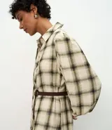 Vestido largo de corte midi, confeccionado en tejido de viscosa con estampado de cuadros. Presenta cuello camisero, cierre frontal abotonado, mangas largas abullonadas y falda con volados. Incluye un cinturón fino para ajustar a la cintura.