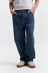 Jean de corte baggy con tiro medio, diseño amplio y holgado en piernas y cadera, con pasacintos y cierre frontal.