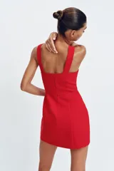 Vestido corto de color rojo con escote corazón estilo corsetero, tirantes anchos y falda con corte evasé. Cuenta con cierre de cremallera oculto en la espalda.