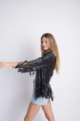 Campera corta de cuero sintético negro, con solapas, mangas 3/4 con tachas y flecos.