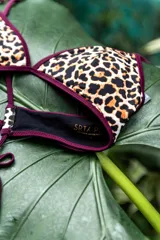 Conjunto de bikini compuesto por un corpiño triangular y una bombacha de corte clásico. El diseño presenta una combinación de colores en bordó, con detalles de ribetes en rosa y mostaza en los bordes y tirantes.