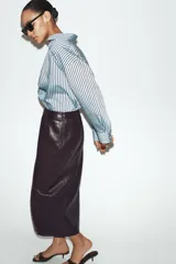 Camisa de corte oversize con estampado de rayas verticales en tonos celeste y negro. Presenta cuello solapa, cierre frontal con botones y mangas largas con puños rectos.