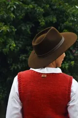 Sombrero marrón de ala ancha confeccionado en paño de lana afieltrada a mano, con cinta decorativa del mismo material alrededor de la copa.