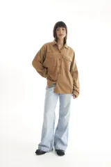 Camisa negra de pana, corte oversize, con cuello camisero, cierre frontal con botones, dos bolsillos con solapa en el pecho y mangas largas con puños abotonados.