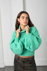 Polera de tejido de punto color verde menta, con cuello alto, mangas largas abullonadas y puños y cintura acanalados.