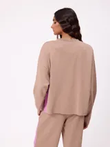 Sweater de corte oversize y estilo cropped, color gris oscuro, con cuello redondo y detalle de costura en forma de X en el pecho. Presenta un pequeño logo bordado en el ruedo inferior.