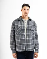 Sobrecamisa de franela a cuadros en tonos grises, negros y blancos, con forro interior de corderito, cierre frontal con botones, cuello clásico y dos bolsillos frontales con solapa.