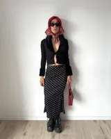 Pollera midi de seda con estampado de lunares blancos sobre fondo negro, de corte al bies y ajuste al cuerpo.