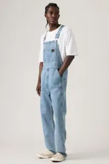 Jardinera de jean en corte holgado, con tirantes ajustables, múltiples bolsillos funcionales y cierre de botones laterales.