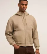 Campera con capucha de estilo urbano, confeccionada en sarga de algodón con efecto lavado. Presenta cierre frontal por cremallera, bolsillos tipo canguro, mangas largas con puños ajustados y bajo elástico. Incluye forro interior de poliéster.
