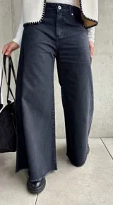 Jean de corte oxford y tiro medio, color negro lavado. Presenta diseño de pierna ancha con costuras verticales decorativas y ruedo deshilachado.