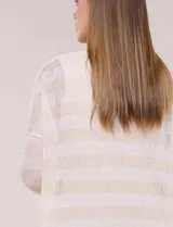 Buzo de tejido calado a rayas horizontales en tonos beige y blanco, de corte holgado, mangas cortas y escote redondo. Incluye musculosa interna básica en color beige.