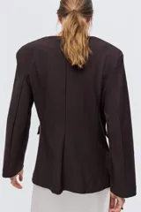 Blazer de punto marrón oscuro, de corte entallado con hombreras, escote en V sin cuello, cierre de un solo botón y bolsillos frontales con solapa.