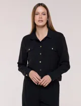 Camperita liviana de corte recto y acabado crepé color blanco, con cuello camisero clásico y cierre frontal de botones metálicos dorados. Presenta bolsillos en el pecho con solapa y mangas largas con puños abotonados.