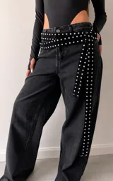 Cinto de terciopelo negro con tachas metálicas plateadas distribuidas a lo largo de toda la pieza.