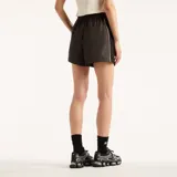 Short New Balance de mujer modelo Trackside, color gris oscuro, con cintura elástica y ribetes contrastantes en los laterales. Presenta el logo de la marca bordado en la pierna izquierda.
