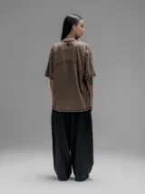 Remera de manga corta con diseño oversize, confeccionada en algodón con proceso batik artesanal en tono óxido. Presenta recortes superpuestos en el frente y costuras expuestas en mangas y cuerpo.