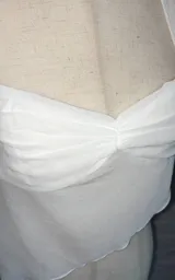 Top blanco de microtul con breteles finos y corte asimétrico.