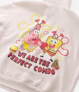 Buzo con capucha de corte boxy, color beige, con bolsillo canguro frontal y estampa bordada de Bob Esponja y Patricio en el pecho. Presenta puños y cintura acanalados, y cordones ajustables en la capucha.