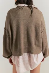 Cárdigan de silueta oversized confeccionado en hilo de algodón, color beige. Presenta escote en V, cierre frontal con botones, hombros caídos y mangas largas amplias con terminaciones acanaladas.