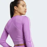 Remera corta de entrenamiento Adidas de color lila, con diseño sin costuras y ajuste ceñido. Posee cuello redondo, mangas largas con las tres tiras características de la marca y dobladillo acanalado.