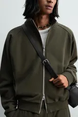 Bolso bandolera negro de piel con textura, cierre de solapa con imán y cremallera. Incluye bolsillo interior con cremallera y bolsillo plano. Asa de hombro ajustable de piel.