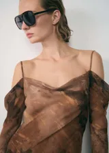 Vestido midi de tejido ligero con estampado abstracto en tonos marrones. Presenta un diseño con escote drapeado, tirantes finos y mangas largas caídas que dejan los hombros al descubierto.