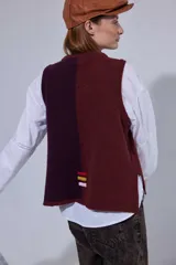 Chaleco de tejido de punto con diseño de bloques de color en tonos tierra, incluyendo marrón, verde oliva y beige. Presenta un panel central con textura tejida y cuello redondo.