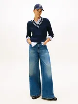 Sweater de punto color azul marino, con cuello en V ribeteado con dos franjas blancas. Presenta tejido trenzado (cableado) en el frente y puños y dobladillo acanalados.