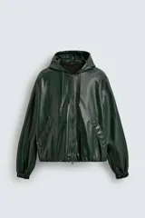 Cazadora de corte relajado confeccionada en material efecto piel color verde oscuro. Cuenta con capucha ajustable con cordones, cierre frontal de cremallera, bolsillos laterales de vivo y puños con elástico.