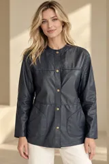 Camisa de cuero azul oscuro, de manga larga, con cuello redondo a la base, cierre frontal con broches metálicos y bolsillos aplicados en los costados.
