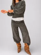 Pantalón sastrero de corte recto y tiro medio-alto, con estampado de cuadros en tonos grises y marrones. Presenta una cintura elástica que aporta comodidad y una textura de tela abrigada.