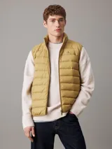 Chaleco inflable color ocre con cierre frontal y cuello alto. Tiene el logo de la marca bordado en el pecho.